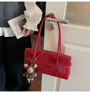 Detail of red suede shoulder bag with silver buckle and cute brown bear charm