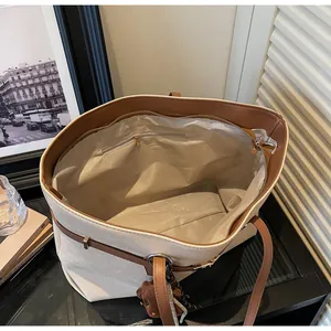 Interior view of large white canvas tote bag with brown leather straps and inner pocket