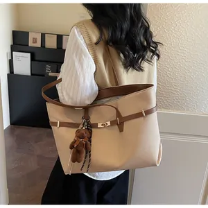Detail view of large beige canvas tote bag featuring brown straps and a cute plush bear charm