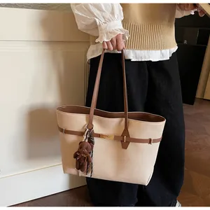 Detail of canvas tote bag featuring brown leather trim, gold twist lock and bear charm