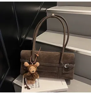 Detail of dark brown suede shoulder bag with bear pendant on a staircase setting