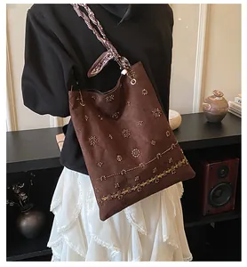 Detail of bohemian suede tote bag featuring heavy beaded embroidery and silk scarf handle