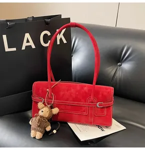 Detail of red vintage suede underarm bag with a cute bear charm on a black leather background