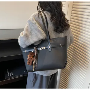Classic black tote bag detail featuring silver buckle and cute brown bear pendant
