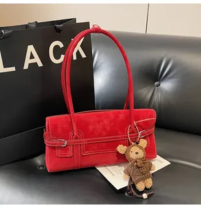 Detail of red vintage underarm bag with plush teddy bear charm on leather background