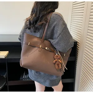 Detail showing high-capacity leather tote bag with silver buckle and plush bear charm