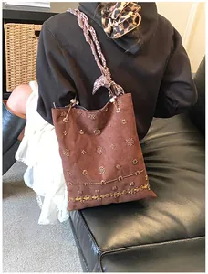 Close-up of bohemian brown suede tote with gold beadwork and floral scarf handle detail
