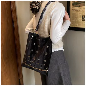 Detail of black suede tote bag with golden embroidery and ethnic pattern silk scarf