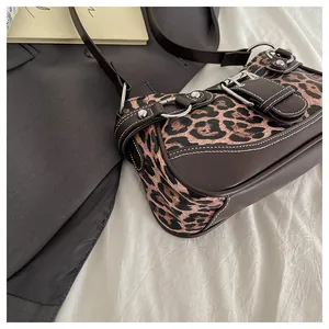 Detailed view of leopard print shoulder bag with vintage silver buckles and white stitching
