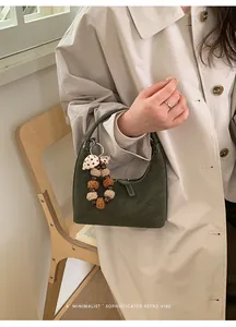 Dunkelgrüne Wildleder-Halbmondtasche mit Plüsch-Anhänger in schickem, minimalistischem Design