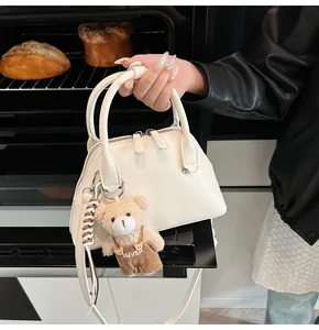 Close-up of cream white Boston bag with cute bear charm and silver zipper details