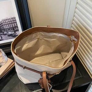Large off-white canvas tote bag with brown leather handles and a plush bear pendant