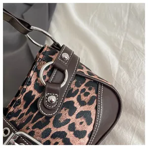 Detail view of leopard print canvas and brown leather stitching with silver ring buckle