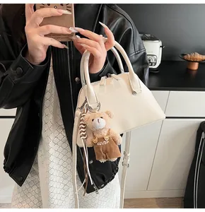 Detailed close-up of a white textured shell bag with cute plush bear charm accessory