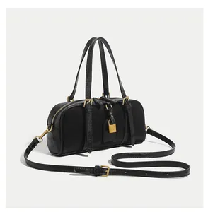 Detail of black leather Boston bag featuring gold hardware and adjustable shoulder strap