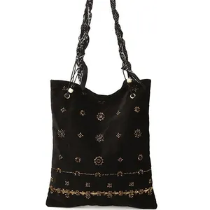 Ethnic tote bag with gold beads, quilted suede, and scarf-wrapped handle on white background