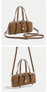 Close-up of brown Boston bag with golden padlock detail and dual handle texture