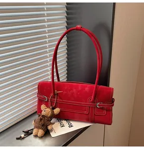 Detail of red rectangular shoulder bag with white stitching and cute bear charm