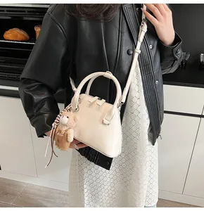Detail of cream shell bag with cute bear charm and adjustable strap for women
