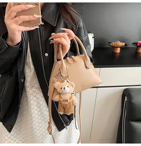 Detail of apricot shell bag with smooth leather finish and cute teddy bear pendant