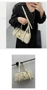 Detailed view of cream Boston bag with gold padlock charm and adjustable buckle straps