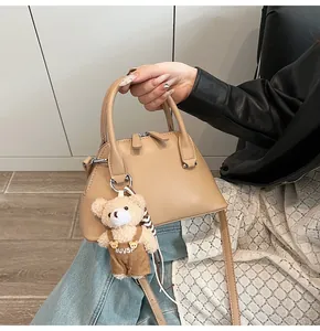 Detail of shell shoulder bag with cute teddy bear pendant and crossbody strap