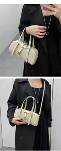 Detail view of cream Boston bag featuring gold padlock and textured faux leather finish