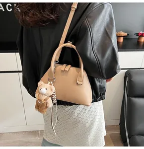 Detail of apricot shell handbag with a cute teddy bear charm and sleek leather strap