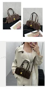 Detail view of brown Boston bag with golden padlock and adjustable shoulder strap
