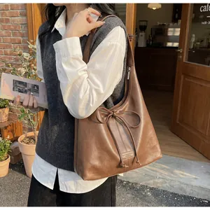 Close-up of vintage brown tote bag with leather texture and decorative bow detail