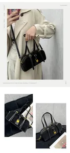Close-up of black leather Boston bag with golden hardware lock and chain details
