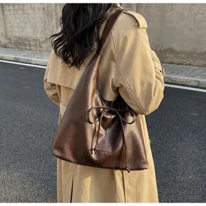 Detail of dark brown tote bag with leather bow decoration and rectangular brand tag