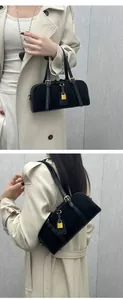 Detail of a black Boston bag featuring gold hardware, decorative straps, and a padlock charm