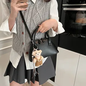 Minimalist black shell crossbody bag with bear charm and adjustable shoulder strap