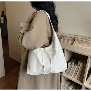 Detailed close-up of cream white tote bag with bow drawstring and silver zipper detail