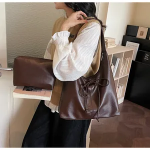 Detail of dark brown leather tote and inner pouch set with minimalist bow decoration