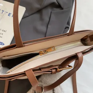 Dettaglio interno di una borsa tote in pelle scamosciata marrone con ampia capacità e zip