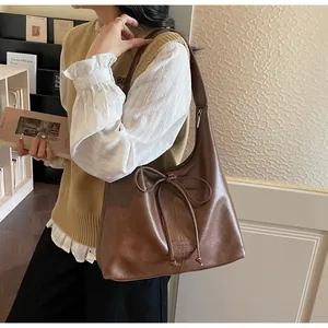 Detail of vintage brown leather tote bag with bow drawstring and wide shoulder strap