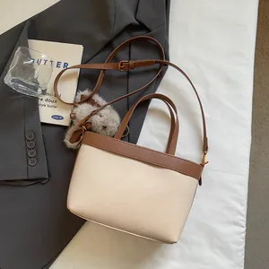 Dettaglio della borsa patchwork con manici a contrasto marroni e ciondolo peluche
