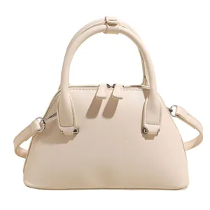 Elegant beige shell shoulder bag with dual handles and silver hardware on white background
