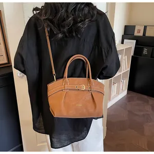 Detail of vintage brown leather handbag with pleats and gold metal buckle on shoulder strap