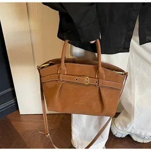 Close-up of the pleated brown handbag with a gold buckle and adjustable strap