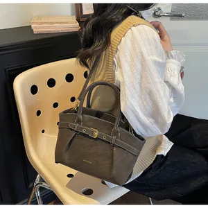 Detail of a dark brown textured leather tote bag with a golden buckle and a slim shoulder strap