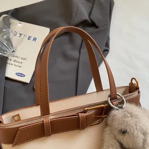 Dettaglio della borsa tote in ecopelle con cuciture scamosciate e ciondolo a coniglietto