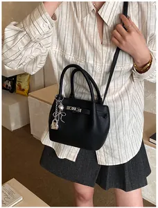 Detail der schwarzen Beuteltasche aus genarbtem Leder mit Schnalle und Herz-Anhängern