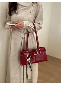 Detail der dunkelroten Retro-Schultertasche mit silbernem Bogen- und Perlenanhänger