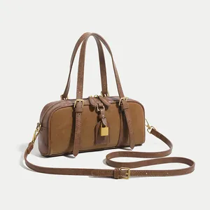 Classic dark brown Boston bag with dual handles and gold decorative hardware details