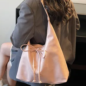 Pink vintage hobo tote bag with a bow detail, worn by a model in a grey blazer jacket