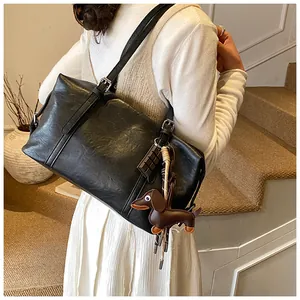 Black vintage leather underarm tote bag with a brown dachshund charm and silver hardware