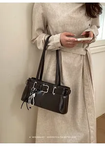 Details einer dunkelbraunen Retro-Achseltasche mit Schnalle und Perlenstern-Anhänger